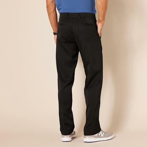 Person wearing black pants and gray sneakers, back view.