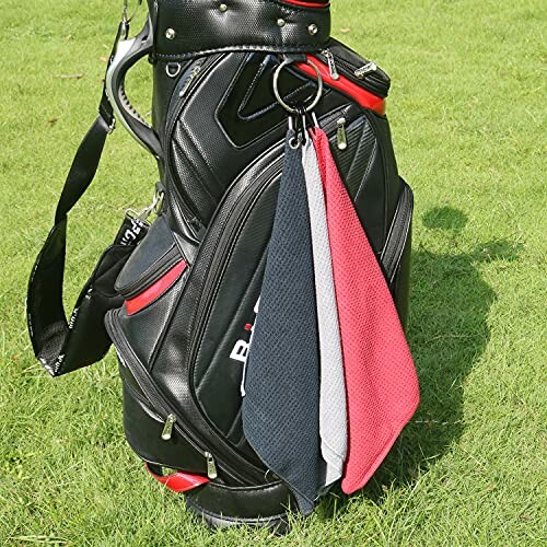 Golf bag with three hanging towels on grass