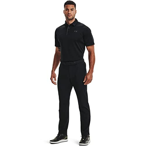 Man wearing black golf apparel with a polo shirt and pants.