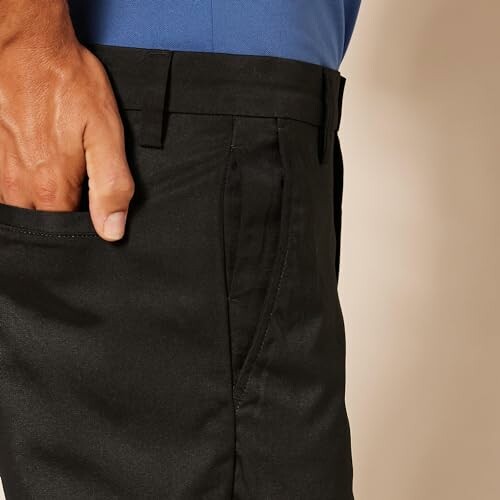 Close-up of a person wearing black pants with a hand in the pocket.